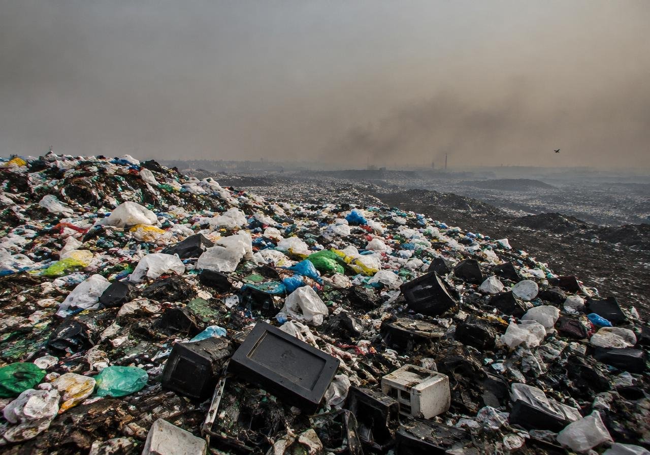 Landfill of plastic and electronic waste under a smoggy sky